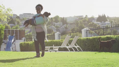Video-of-happy-african-american-grandmother-carrying-granddaughter,-playing-in-park,-copy-space
