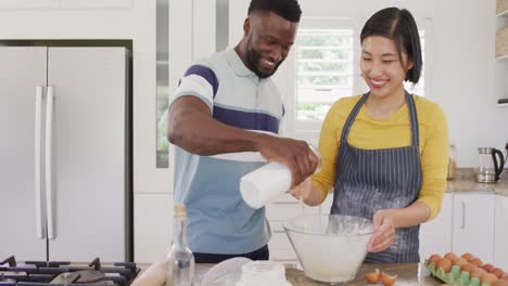 Happy-diverse-couple-wearing-apron-and-baking-in-kitchen