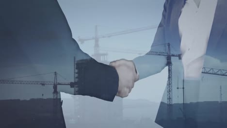 Animation-of-cityscape-with-construction-site-over-business-people-shaking-hands