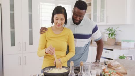 Happy-diverse-couple-cooking-and-preparing-breakfast-in-kitchen