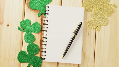 Video-of-st-patrick's-green-shamrock-and-notebook-with-copy-space-on-wooden-background
