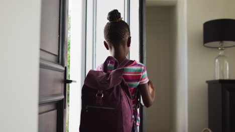 Video-Eines-Glücklichen-Afroamerikanischen-Mädchens-Mit-Schultasche,-Das-Die-Haustür-öffnet-Und-Das-Haus-Zur-Schule-Verlässt