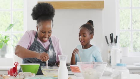 Happy-african-american-grandmother-and-granddaughter-baking-and-dancing-in-kitchen,-copy-space