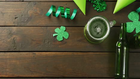 Video-of-st-patrick's-green-beer,-shamrock-and-bottle-on-wooden-background