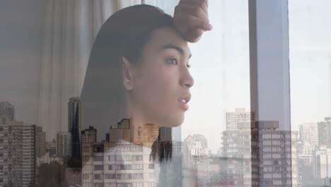 Animation-of-cityscape-over-biracial-woman-looking-through-window