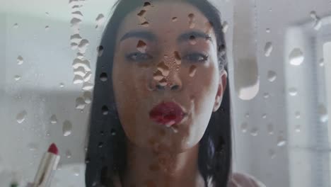 Animation-of-water-drops-over-biracial-woman-applying-lipstick