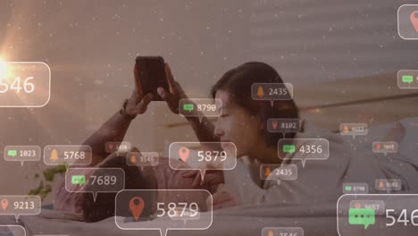 Animation-of-social-media-icons-with-numbers-over-diverse-couple-using-smartphone