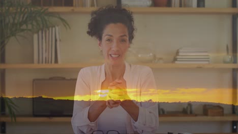 Animation-of-sunset-landscape-over-biracial-woman-talking-to-camera