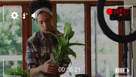 Animation-of-digital-screen-interface-over-biracial-woman-potting-plant