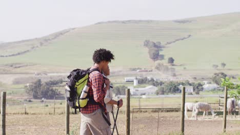 Happy-african-american-couple-with-backpacks,-hiking-with-trekking-poles-together,-slow-motion