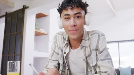 Portrait-of-happy-biracial-male-teenage-boy-having-video-call-at-home,-slow-motion