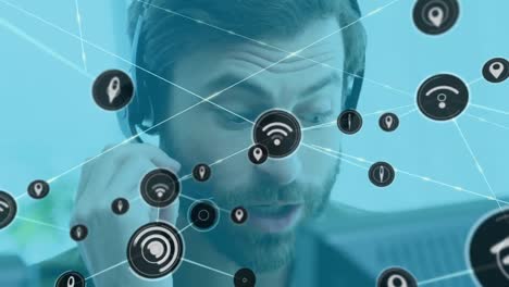 Animation-of-network-of-connections-with-icons-over-caucasian-businessman-using-phone-headset