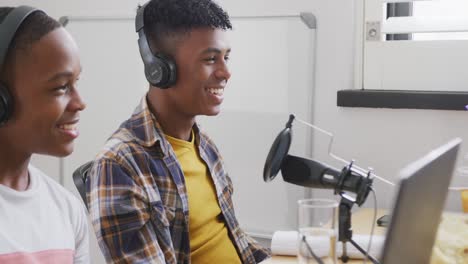 Happy-african-american-male-teenage-friends-using-laptop-and-recording-podcast,-slow-motion