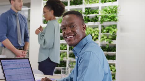 Portrait-of-happy-african-american-businessman-looking-at-camera-and-smiling-at-office,-slow-motion