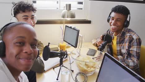 Portrait-of-happy-diverse-male-teenage-friends-using-laptop-and-recording-podcast,-slow-motion