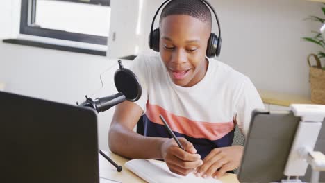 Happy-african-american-male-teenage-boy-recording-podcast-using-laptop,-slow-motion