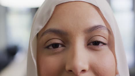 Portrait-of-biracial-businesswoman-wearing-hijab-in-office,-slow-motion