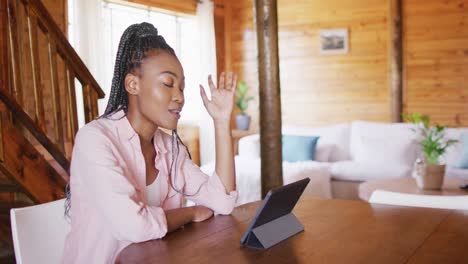 Feliz-Mujer-Afroamericana-Sentada-En-La-Mesa-Y-Usando-Tableta-Para-Videollamada,-Cámara-Lenta