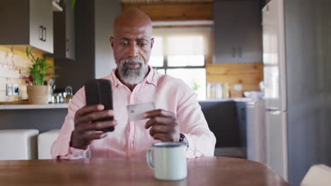 Glücklicher-älterer-Afroamerikanischer-Mann-In-Blockhütte,-Der-Sein-Smartphone-Zum-Online-Shopping-Nutzt,-Zeitlupe