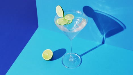 Close-up-of-transparent-drink-with-lime-on-blue-background