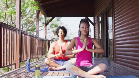 Feliz-Pareja-Afroamericana-Haciendo-Yoga-Y-Meditando-En-Cabaña-De-Madera,-Cámara-Lenta