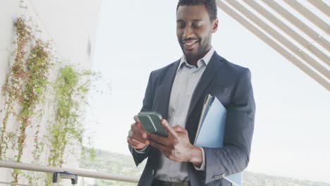 Happy-african-american-businessman-using-smartphone-and-celebrating-at-office,-slow-motion