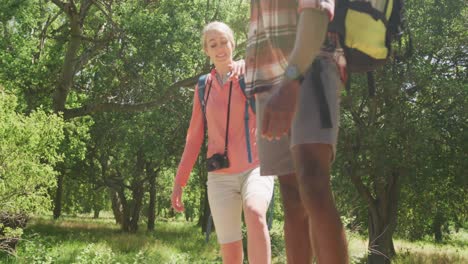 Happy-diverse-couple-hiking-with-backpacks-in-park,-slow-motion