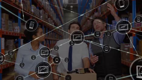 Animation-of-connected-laptop-and-phone-icons,-caucasian-coworkers-discussing-inventory-in-warehouse