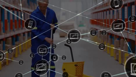 Animation-of-connected-phone-and-laptop-icons-over-caucasian-man-cleaning-floor-in-warehouse