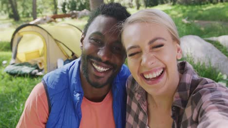 Portrait-of-happy-diverse-couple-camping-in-park,-slow-motion