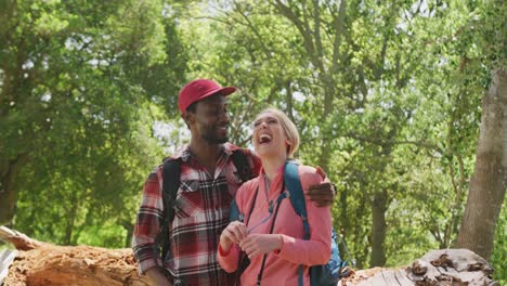 Happy-diverse-couple-with-backpacks-embracing-in-park,-slow-motion