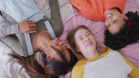 Happy-diverse-teenager-girls-friends-laughing-and-lying-on-bed,-slow-motion