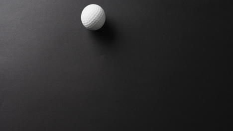 Close-up-of-golf-ball-on-black-background,-copy-space,-slow-motion