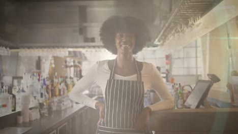 Animation-of-portrait-of-african-american-female-shop-assistant-with-apron-over-light-spots