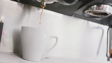 Close-up-of-working-coffee-machine-pouring-fresh-coffee-into-cup-at-cafe
