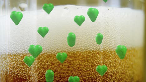 Animation-of-st-patrick's-day-green-hearts-on-glass-with-beer-background