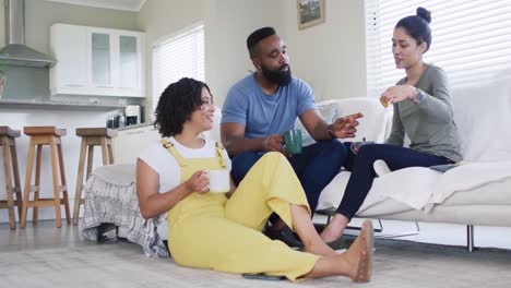 Diverse-male-and-female-friends-talking-and-having-tea-at-home-in-slow-motion