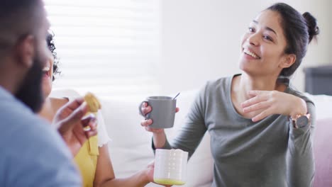 Diverse-male-and-female-friends-talking-and-having-tea-at-home-in-slow-motion