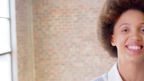 Half-face-portrait-of-biracial-casual-businesswoman-with-afro-in-office,-copy-space,-slow-motion