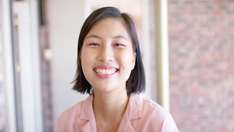 Portrait-of-smiling-casual-asian-businesswoman-in-office,-in-slow-motion
