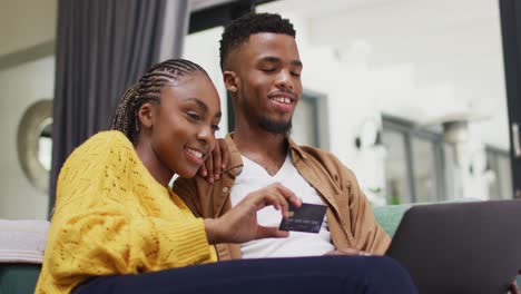 Glückliches-Afroamerikanisches-Paar,-Das-Auf-Dem-Sofa-Sitzt-Und-Online-Einkauft