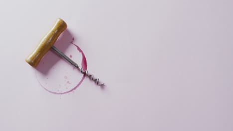 Corkscrew-and-red-wine-stain-on-white-surface-with-copy-space