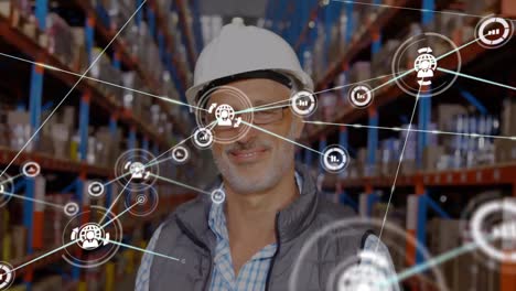 Animation-of-network-of-connections-with-icons-over-caucasian-man-smiling-in-warehouse