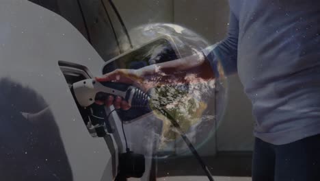 Animation-of-globe-spinning-over-african-american-woman-fueling-car