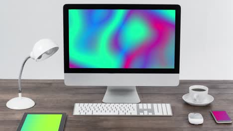 Animation-of-technological-devices-with-colorful-moving-shapes-on-screen-on-desk