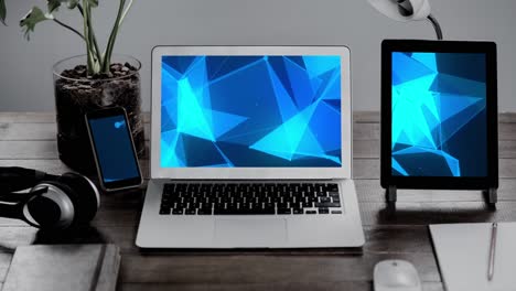 Animation-of-technological-devices-with-blue-shapes-on-screen-on-desk