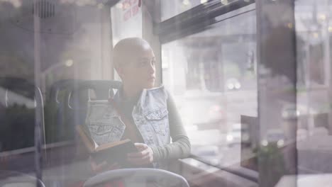 Animation-of-cars-on-street-over-biracial-woman-reading-book-in-bus