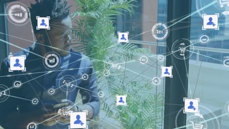 Animation-of-multiple-connected-icons-over-african-american-man-using-cellphone-in-office