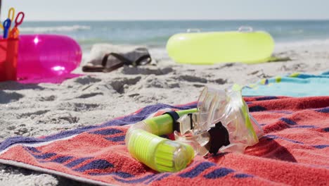 Video-of-snorkeling-mask,-towels-and-beach-equipment-lying-on-beach
