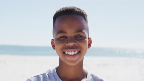Glücklicher-Afroamerikanischer-Junge,-Der-Am-Strand-In-Die-Kamera-Lächelt